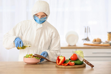 Woman in biohazard suit cooking in kitchen