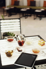 Tea, cakes, organizer and a digital tablet on a table