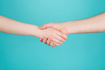 Close-up cropped photo of two persons woman and man holding hands as greeting isolated on turquoise teal blue color bright background