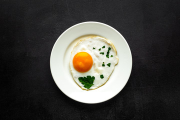 Fried eggs on plate - black background top-down