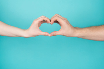 Obraz premium Cropped close-up photo of woman and man making heart with their hands isolated on blue teal bright color background