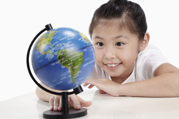 Girl smiling and looking at globe on table