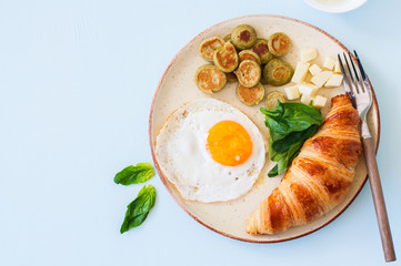 Healthy breakfast, fried eggs with spinach pancake cereals cheese and croissant in a plate.