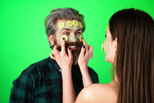 Man Facial Cucumber. Funny Couple With A Clay Mask. Male Bearded Model And Female Model With Clay Mask On The Face.