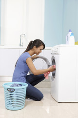 Woman putting clothes into washing machine