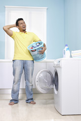 Man scratching head while holding laundry basket
