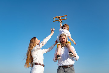 Happy family outdoors, child with toy airplane. People dream about travel. Summer holiday and vacation concept.
