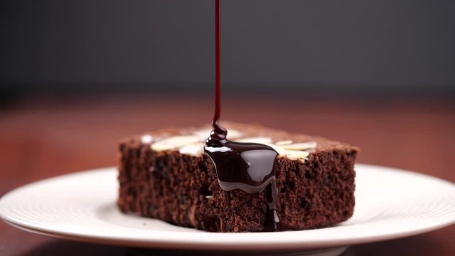 Chocolate pouring on cake in 4K Resolution. Topping chocolate on homemade brownie dessert