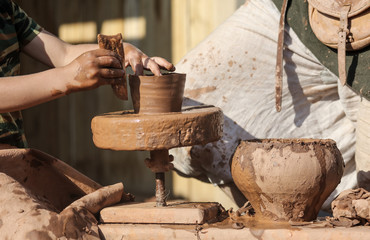 Hands of a man sculpt clay dishes.