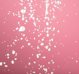Splashes of white milk on a pink background.