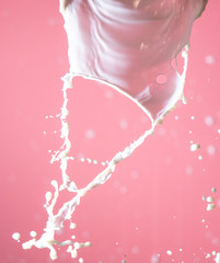 Fototapeta na wymiar Splashes of white milk on a pink background.
