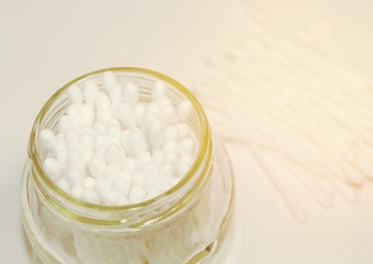White cosmetic cotton buds in a glass jar.