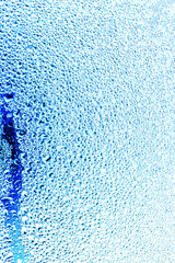 Drops of water on blue glass as an abstract background