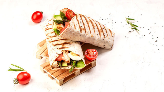 Burritos wraps with asparagus, cherry tomatoes, avocado, chicken fillet on a light background, top view. burrito, mexican food