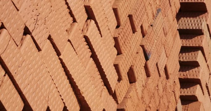 Panorama of warehouse of bricks, many red bricks lie on pallets, folded in herringbone, stored, ready for use, building materials at construction site, suburban house building, bricks have cracked