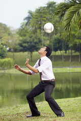 Young businessman heading soccer ball with his head