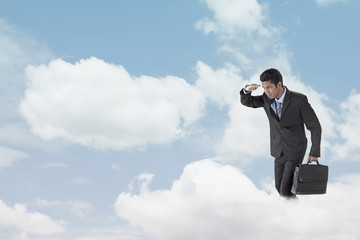 Young businessman standing on clouds, looking below