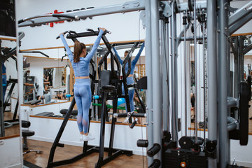 A beautiful young caucasian girl trains on a device in the gym