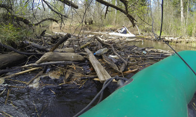 view from a rubber boat on the river, old reeds along the shore and the first greenery