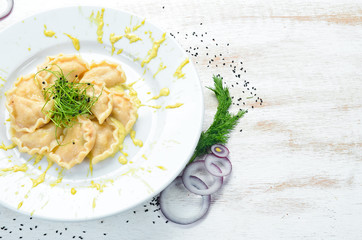 Potato dumplings with sour cream. Ukrainian cuisine. Top view, free space for your text. Rustic style.
