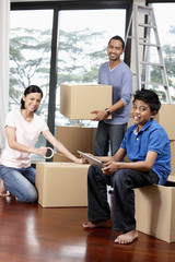 Boy using digital tablet, man and woman packing in the background