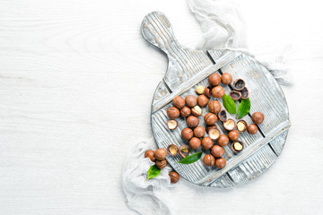 Macadamia nut in bowl on white wooden background.