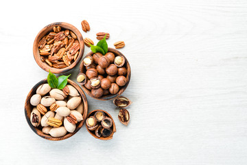 Set of nuts. pecans and macadamia nuts in bowls on a white background. Top view. Free space for your text.