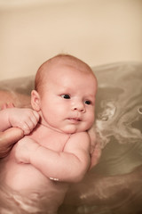 Newborn baby girl being held in the bath