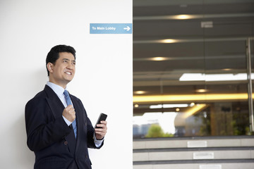 Fototapeta premium Businessman with smart phone in hand, cheering