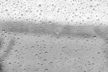 black and white rain water drops on a window glass close up , gray drop macro in a golden light ; backdrop textute background