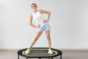 Relaxed woman jumping on trampoline.young fitness girl trains on a mini trampoline in the Studio