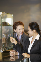Businesswomen looking at items in a display glass