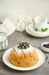 Traditional Italian cake Zuccotto on a white plate decorated with powdered sugar and berries on top. Vertical orientation. Copy space, selective focus.