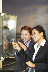 Businesswomen looking at items in a display glass