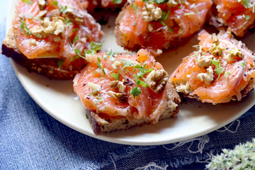 sanduíche aberto com pão de cereais, salmão, ervas e nozes.