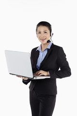 Mid adult businesswoman working on laptop with headset