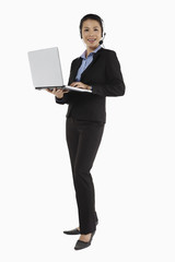 Mid adult businesswoman working on laptop with headset