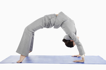 Mid adult businesswoman bending backwards in yoga position