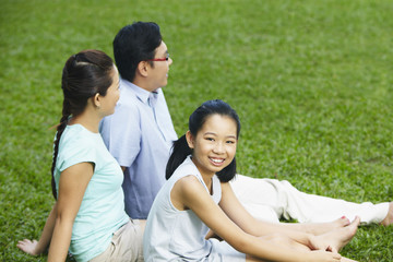 Girl sitting on field with her parents