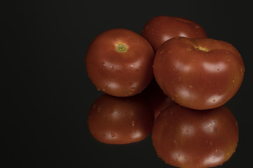 Tomato on black reflective studio background. Isolated black shiny mirror background for every concept.