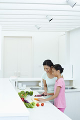 Woman teaching girl to cut vegetables