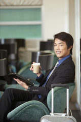 Businessman drinking coffee while using digital tablet