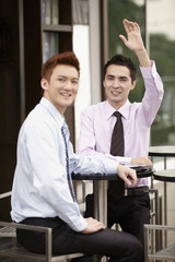 Businessman with arms raised, another businessman smiling