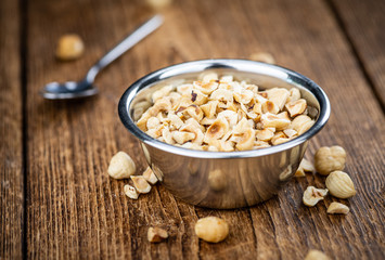 Freshly chopped Hazelnuts on an old wooden table (close up; selective focus)
