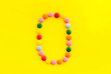 Letter O - alphabet made with sweets on yellow from above