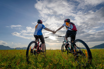 Fototapeta na wymiar family couple lover enjoy the life of riding biking on the fresh field meadow grass, cheerfully life holding hand together on outdoors activity