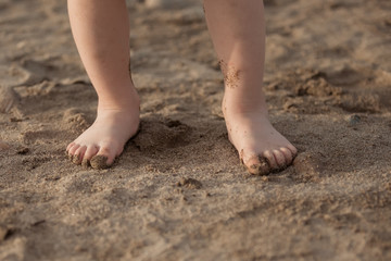 Fototapeta na wymiar Small children's feet stand on the sand in summer.