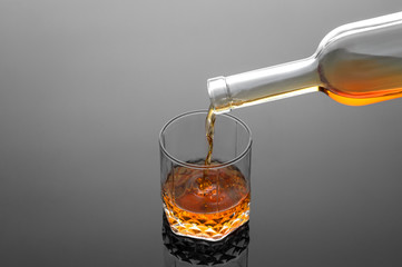 Barman pouring whiskey in glass on grey background, cold atmosphere, time of relax with whisky