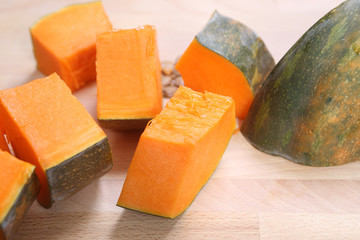 yellow pumpkin cut into pieces on wooden table