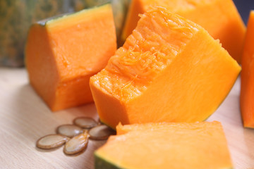 yellow pumpkin cut into pieces on wooden table